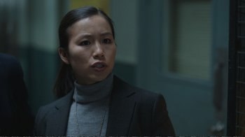 Movie still from “Peacemaker” (2022), created by James Gunn – A woman wearing a suit and a necklace; Close Up shot, Over the shoulder angle