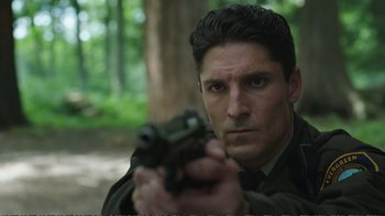 Movie still from “Peacemaker” (2022), created by James Gunn – A person holding a gun; Close Up shot, Low angle