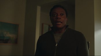 Movie still from “Peacemaker” (2022), created by James Gunn – A man standing in a dark room looking at the camera; Close Up shot, Low angle