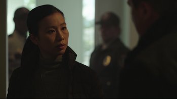 Movie still from “Peacemaker” (2022), created by James Gunn – A woman standing next to two men in a room; Close Up shot, Over the shoulder angle