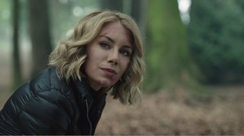 Movie still from “Peacemaker” (2022), created by James Gunn – A beautiful blonde haired woman in the woods; Close Up shot, Over the shoulder angle
