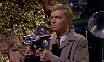 Movie still from “Peeping Tom” (1960), directed by Michael Powell – A man in a suit and tie holding a camera; Medium shot, Low angle