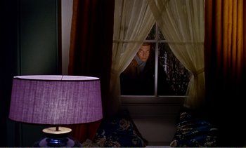 Movie still from “Peeping Tom” (1960), directed by Michael Powell – A man looking out of a window at night; Wide shot, High angle