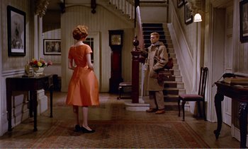 Movie still from “Peeping Tom” (1960), directed by Michael Powell – A man and a woman standing in front of a staircase; Wide shot, High angle