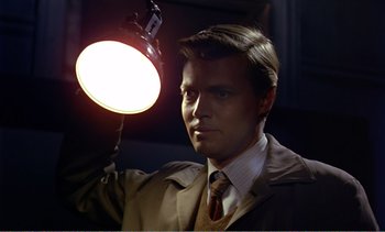Movie still from “Peeping Tom” (1960), directed by Michael Powell – A man holding a light in a dark room; Close Up shot, Low angle