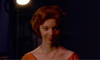 Movie still from “Peeping Tom” (1960), directed by Michael Powell – A woman with red hair wearing an orange dress; Close Up shot, Low angle