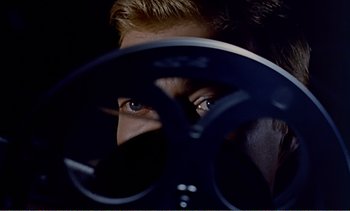 Movie still from “Peeping Tom” (1960), directed by Michael Powell – A man's face with a fan in front of him; Extreme Close Up shot, Overhead angle