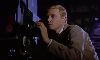 Movie still from “Peeping Tom” (1960), directed by Michael Powell – A man looking into a projector with a flashlight; Close Up shot, Low angle
