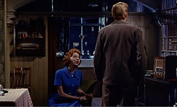 Movie still from “Peeping Tom” (1960), directed by Michael Powell – A man and a woman are standing in front of each other; Medium shot, Over the shoulder angle