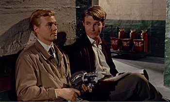 Movie still from “Peeping Tom” (1960), directed by Michael Powell – A couple of men sitting next to each other on the ground; Medium shot, Over the shoulder angle