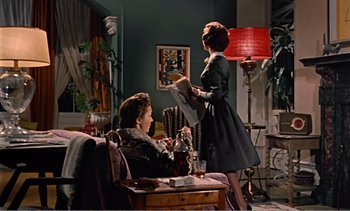 Movie still from “Peeping Tom” (1960), directed by Michael Powell – A woman standing next to a man sitting on a couch; Wide shot, Low angle