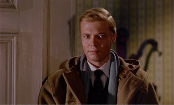 Movie still from “Peeping Tom” (1960), directed by Michael Powell – A man wearing a coat and tie standing in front of a wall; Close Up shot, Over the shoulder angle