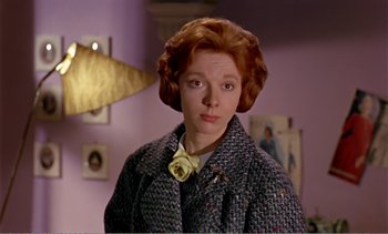 Movie still from “Peeping Tom” (1960), directed by Michael Powell – A woman with a flower in her hair and wearing a coat; Close Up shot, Over the shoulder angle