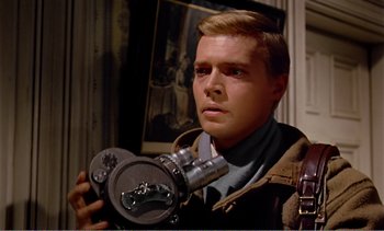 Movie still from “Peeping Tom” (1960), directed by Michael Powell – A man holding a camera in front of a painting; Close Up shot, Low angle