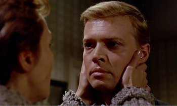 Movie still from “Peeping Tom” (1960), directed by Michael Powell – A man looking into a mirror while holding his hand to his ear; Close Up shot, Over the shoulder angle