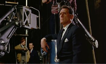 Movie still from “Peeping Tom” (1960), directed by Michael Powell – A man in a suit and tie sitting in front of a camera; Medium shot, Low angle