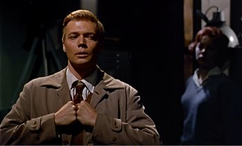 Movie still from “Peeping Tom” (1960), directed by Michael Powell – A man in a trench coat holding his tie; Medium shot, Low angle