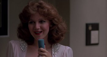 Movie still from “Peggy Sue Got Married” (1986), directed by Francis Ford Coppola – A woman holding a microphone in her hand; Close Up shot, Low angle