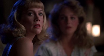 Movie still from “Peggy Sue Got Married” (1986), directed by Francis Ford Coppola – A woman with blonde hair looking at the camera with another woman in the background; Close Up shot, Over the shoulder angle