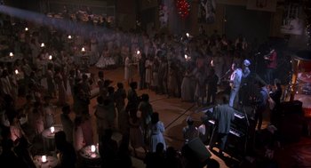 Movie still from “Peggy Sue Got Married” (1986), directed by Francis Ford Coppola – A group of people standing in a large room; Wide shot, High angle