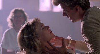 Movie still from “Peggy Sue Got Married” (1986), directed by Francis Ford Coppola – A young woman being held down by a man; Close Up shot, Over the shoulder angle