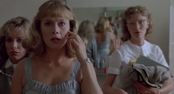 Movie still from “Peggy Sue Got Married” (1986), directed by Francis Ford Coppola – A woman talking on a cell phone in front of other women; Close Up shot, Low angle