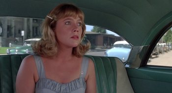 Movie still from “Peggy Sue Got Married” (1986), directed by Francis Ford Coppola – A woman sitting in the back seat of a car; Close Up shot, Over the shoulder angle