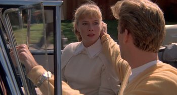 Movie still from “Peggy Sue Got Married” (1986), directed by Francis Ford Coppola – A woman sitting in front of a man in front of a mirror; Close Up shot, Over the shoulder angle