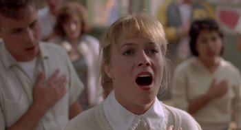 Movie still from “Peggy Sue Got Married” (1986), directed by Francis Ford Coppola – A woman with her mouth wide open singing in front of a group of people; Close Up shot, Low angle