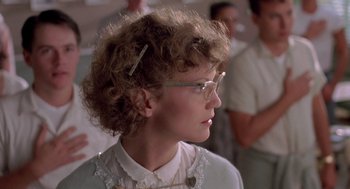 Movie still from “Peggy Sue Got Married” (1986), directed by Francis Ford Coppola – A young woman wearing glasses and a white shirt; Close Up shot, Over the shoulder angle