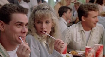 Movie still from “Peggy Sue Got Married” (1986), directed by Francis Ford Coppola – A woman is holding a straw in her mouth while sitting in a crowd; Close Up shot, Over the shoulder angle