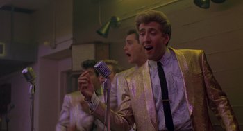 Movie still from “Peggy Sue Got Married” (1986), directed by Francis Ford Coppola – A group of young men singing into microphones; Medium shot, Low angle