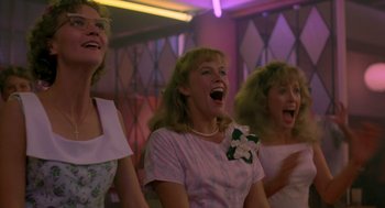 Movie still from “Peggy Sue Got Married” (1986), directed by Francis Ford Coppola – A group of women singing in front of a purple light; Medium shot, Low angle