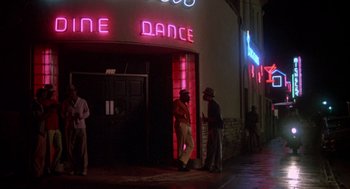 Movie still from “Peggy Sue Got Married” (1986), directed by Francis Ford Coppola – Two men standing in front of a dance studio; Wide shot, Low angle