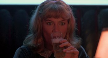 Movie still from “Peggy Sue Got Married” (1986), directed by Francis Ford Coppola – A woman is drinking a glass of beer at a bar; Close Up shot, Over the shoulder angle