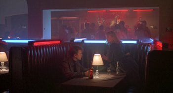 Movie still from “Peggy Sue Got Married” (1986), directed by Francis Ford Coppola – A man and a woman sitting at a table in front of a crowd; Wide shot, High angle