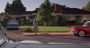 Movie still from “Peggy Sue Got Married” (1986), directed by Francis Ford Coppola – A woman standing on the side of the road near a tree; Extreme Wide shot, Low angle