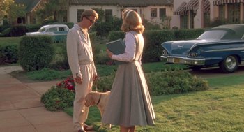 Movie still from “Peggy Sue Got Married” (1986), directed by Francis Ford Coppola – A man and a woman standing next to each other on a sidewalk; Wide shot, Low angle
