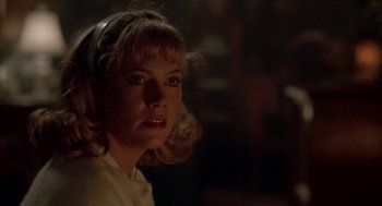 Movie still from “Peggy Sue Got Married” (1986), directed by Francis Ford Coppola – A young woman with blonde ringlets in a dark room; Close Up shot, Low angle