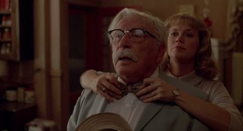 Movie still from “Peggy Sue Got Married” (1986), directed by Francis Ford Coppola – An older man wearing a bow tie while a woman puts on a bow tie; Close Up shot, Low angle