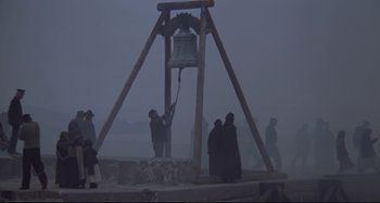 Movie still from “Pelle the Conqueror” (1987), directed by Bille August – A group of people standing next to a large bell; Wide shot, Low angle
