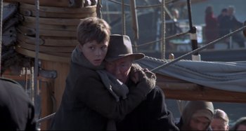 Movie still from “Pelle the Conqueror” (1987), directed by Bille August – A man and a boy are hugging on a boat; Medium shot, Over the shoulder angle