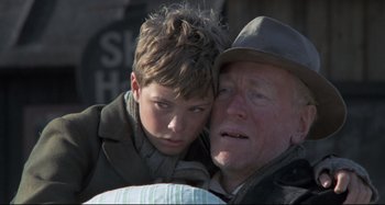 Movie still from “Pelle the Conqueror” (1987), directed by Bille August – An older man and a young boy are posing for a picture; Close Up shot, Low angle