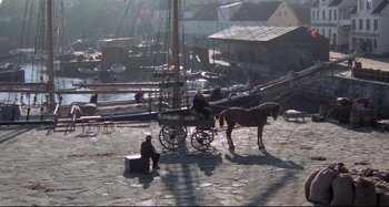 Movie still from “Pelle the Conqueror” (1987), directed by Bille August – A man sitting on the ground next to a horse drawn carriage; Extreme Wide shot, High angle