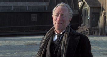 Movie still from “Pelle the Conqueror” (1987), directed by Bille August – An older man wearing a black coat and a black tie; Close Up shot, Low angle