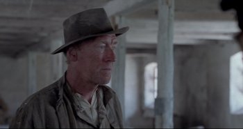 Movie still from “Pelle the Conqueror” (1987), directed by Bille August – A man wearing a hat standing in an unfinished room; Close Up shot, Low angle