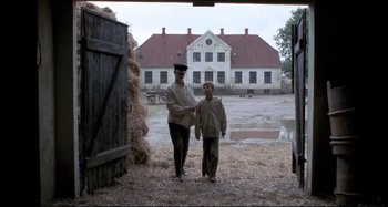 Movie still from “Pelle the Conqueror” (1987), directed by Bille August – A man and a boy are standing in front of a barn; Wide shot, Over the shoulder angle