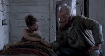 Movie still from “Pelle the Conqueror” (1987), directed by Bille August – An older man and a young boy sitting on a bed; Medium shot, Over the shoulder angle