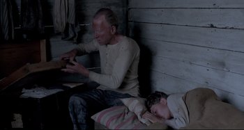 Movie still from “Pelle the Conqueror” (1987), directed by Bille August – An older man and a young boy sitting next to each other; Medium shot, High angle