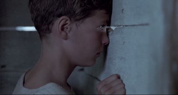 Movie still from “Pelle the Conqueror” (1987), directed by Bille August – A young boy with glasses looking out of a window; Close Up shot, Over the shoulder angle